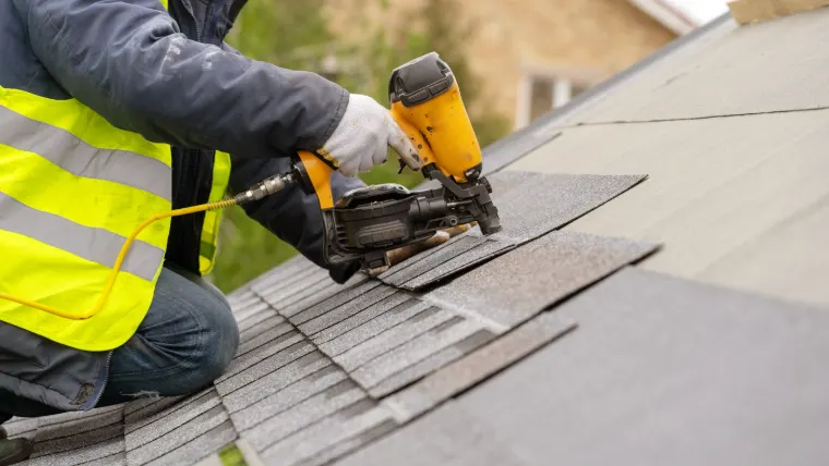 Roofer fastening shingles on a new roof installation in Indiana